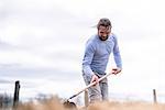 Mature man hoeing in garden