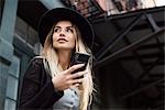 Woman holding mobile phone looking away, New York, USA