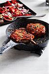 Glazed pork chops in a cast iron skillet with roasted vegetables in the background