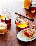 Still life of honey jars with honeycomb and wooden, honey dipper