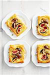 Fig and cheese tarts with honey on white dessert plates