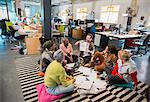 Creative business people meeting, brainstorming in circle on floor in office