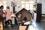 Creative businessman with headphones working at laptop in cubby