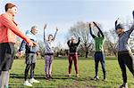 Runners stretching in circle in sunny park