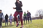 Team cheering woman doing speed ladder drill in sunny park