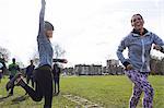 Enthusiastic woman cheering for teammate doing speed ladder drill in park