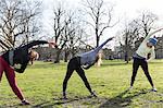 Women runners stretching in sunny park