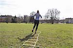 Woman exercising, doing speed ladder drill in sunny park