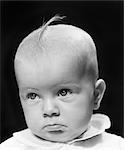 1940s BABY GIRL WITH TUFT OF BLONDE HAIR LOOKING VERY SAD