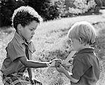 1970s AFRICAN AMERICAN AND CAUCASIAN BOY PLAYING WITH BALSA WOOD TOY AIRPLANE