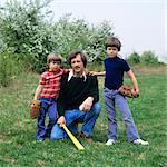 1970s FATHER AND TWO SONS WITH BASEBALL GLOVES AND BAT LOOKING AT CAMERA