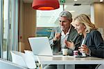 Businesspeople using laptop in cafeteria