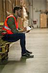 Worker writing on clipboard in warehouse