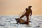 A fisherman rowing with one leg at sunset on Inle Lake, Shan State, Myanmar (Burma), Asia