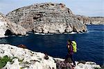A woman hiking above sea cliffs near The Blue Grotto, south Malta, Mediterranean, Europe