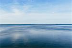 View out to the open sea from the coast. Flat calm water surface.