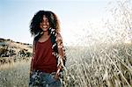 Young woman with curly brown hair hiking in urban park, smiling at camera.
