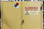 Safety sign reminders mounted to a metal cabinet in a woodworking factory.