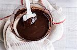 A bowl of chocolate brownie ingredients being stirred by a spatula.