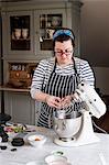 A cook in her kitchen breaking eggs and weighing ingredients for chocolate brownies.