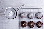 A tray of cooling chocolate brownies, and a sieve with icing sugar for decoration.