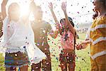 Five young adult friends throwing confetti at Holi Festival