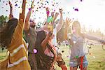 Five young adult friends throwing confetti mid air at Holi Festival