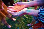 Young woman with cupped hands holding coloured chalk powder at Holi Festival, close up of hands