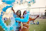 Two young women dancing with blue smoke bombs at Holi Festival