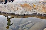 Rock pool reflection of boy running over rock