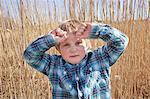 Boy with hands raised in reeds, portrait