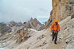 Hiker on dirt track on mountain side, Canazei, Trentino-Alto Adige, Italy