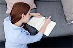 Woman sitting on floor writing in notepad