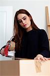 Woman sealing cardboard box with brown tape