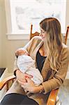 Mother sitting in rocking chair holding newborn baby boy