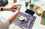 Woman photographing breakfast on mobile phone