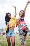Friends drinking and dancing with arms raised in music festival