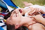 Friends lying on ground, laughing and enjoying music festival