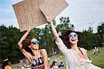 Friends holding up cardboard signs at music festival