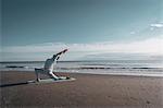 Woman practising yoga on beach