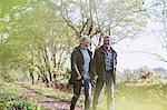 Happy mature couple holding hands, walking in autumn park