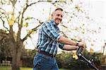 Portrait smiling senior man mowing lawn