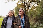 Happy mature couple walking arm in arm in autumn park