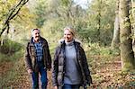 Smiling mature couple walking in sunny autumn woods