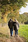 Affectionate mature couple walking in sunny, rural autumn field