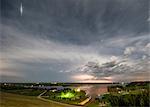 Thunderstorm roars in the distance while a satellite flashes light off its solar panels over rural Nebraska , US