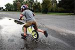 Boy riding bicycle on wet road