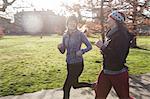 Smiling female runners running in sunny park