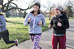 Smiling female runners running in sunny park