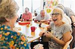 Happy senior woman playing cards with friend in community center